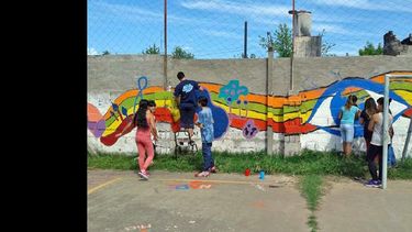 Los jóvenes del Programa participan de la pintada en la pared de la institución. (ENVION)